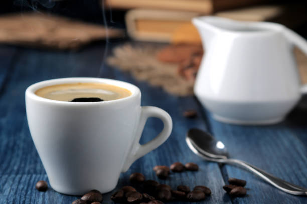 istock Natural espresso coffee in a ceramic coffee cup and coffee beans in the foreground on a blue wooden table. 1354016462