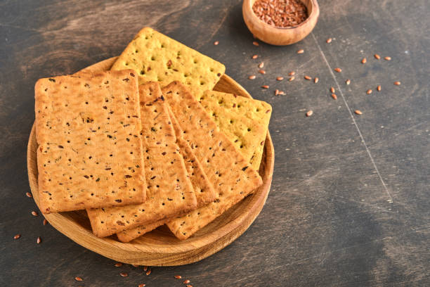 istock Cracker with flax seeds and oat bran rectangular shape for healthy, dietary and balanced diet on dark wooden background. Snack for proper nutrition. 1354016494