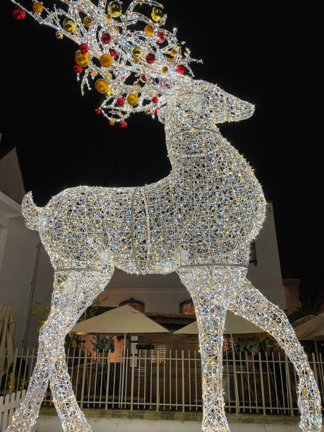 istock Image of artificial, illuminated reindeer statue, Christmas decoration lights at night, red and gold baubles hanging on antlers 1354016546