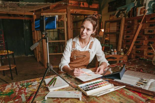 istock Young female artist recording online tutorial using smartphone 1354016553