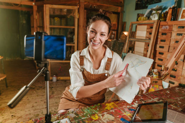 istock Happy smiling young artist working from her art workshop recording master-class 1354017192