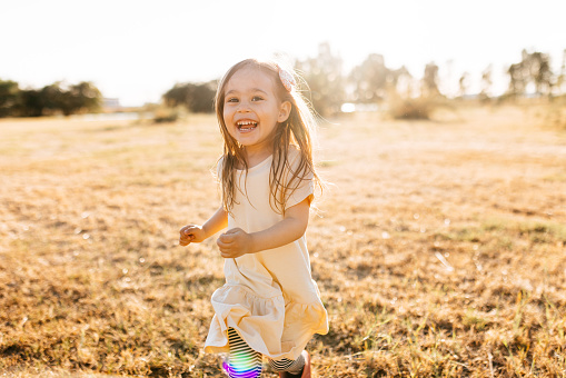 Happy little girl running at sunset. Little girl in nature running and girl in yellow dress