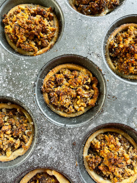 imagem completa da assadeira de muffin de tortas de menta caseiras, sobremesa de natal festiva massa de crosta curta com carne de menta doce (mistura de frutas secas picadas, espíritos destilados e especiarias) coberto com crumble streusel, vista elevada - mince pie crumb christmas food - fotografias e filmes do acervo