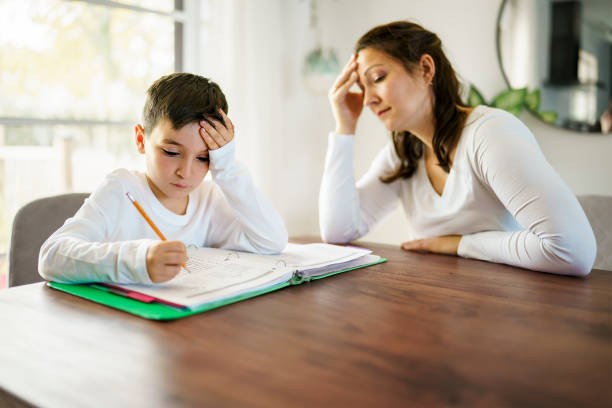 istock mother teaching bored son and helping with homework at home 1354027754