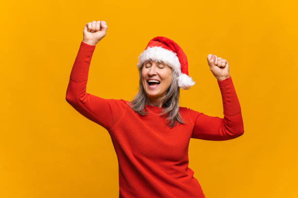 istock Crazy modern mature lady wearing santa hat dancing with eyes closed in ecstatic 1354029719
