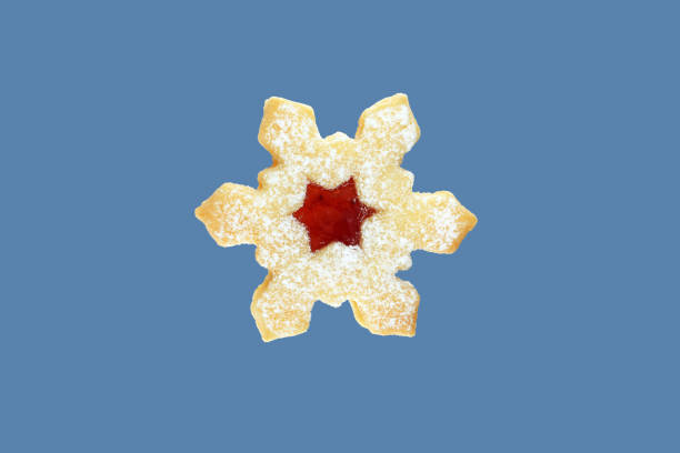 Linzer cookie in a shape of snowflake filled with strawberry jam. Isolated on blue background