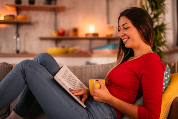istock Woman lying on sofa and reading book 1354030434