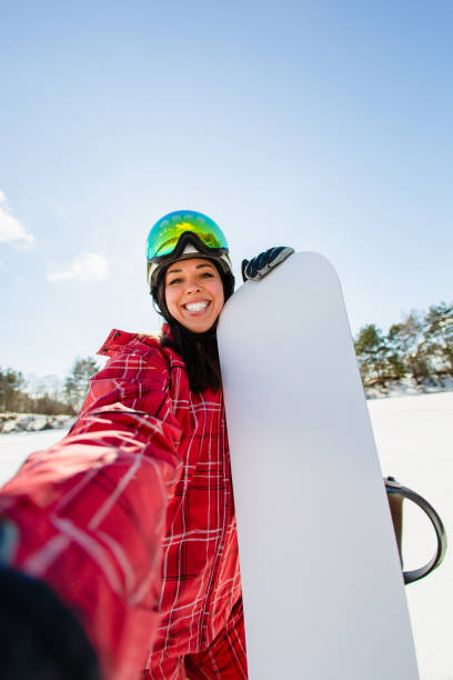 istock Beautiful young woman with the snowboard making selfie 1354031116