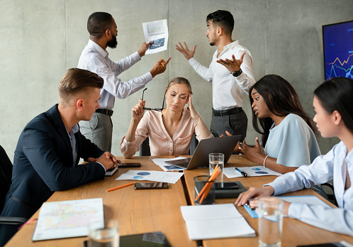 Conflictos en el lugar de trabajo. Grupo estresado de empresarios que tienen desacuerdos durante la reunión corporativa photo