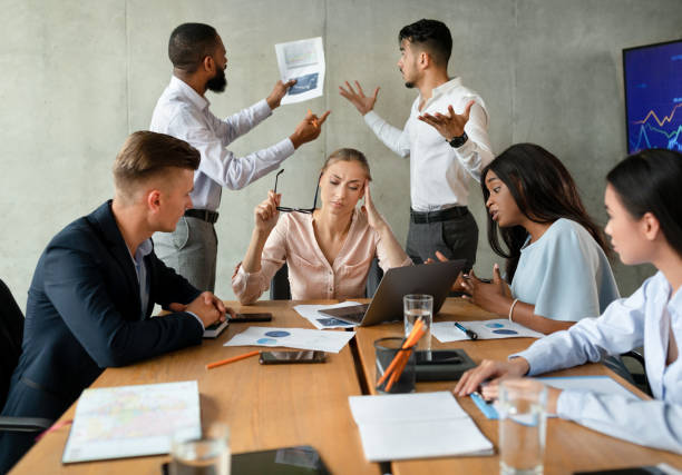 workplace conflicts. stressed group of business people having disagreements during corporate meeting - pijn fotos stockfoto's en -beelden