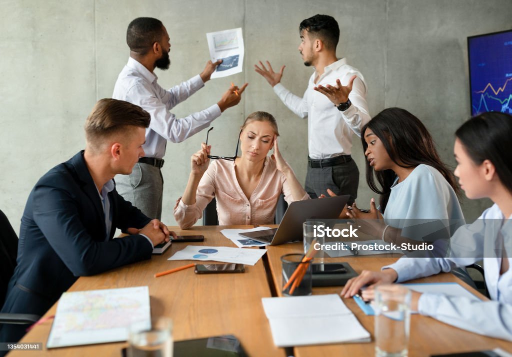 Workplace Conflicts. Stressed Group Of Business People Having Disagreements During Corporate Meeting Workplace Conflicts. Stressed Group Of Business People Having Disagreements During Corporate Meeting, Brainstorming Together In Boardroom, Two Male Coworkers Emotionally Discussing Financial Report Emotional Stress Stock Photo