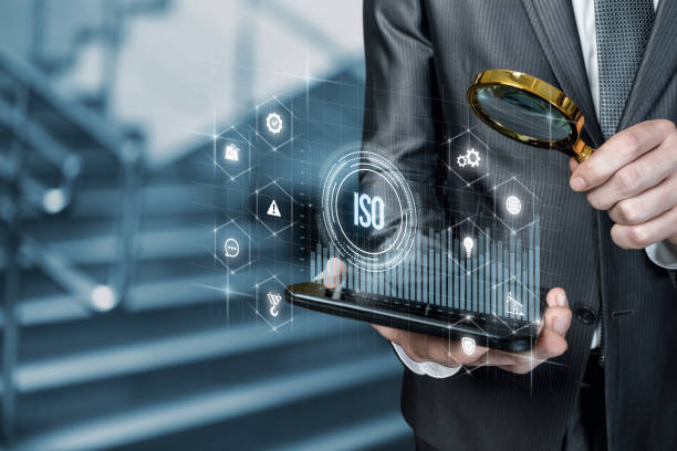 istock Businessman examines structure of ISO standards on tablet on blurred background. 1354032046