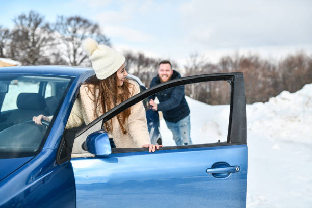 frau und freund schieben auto durch schnee, um es zu lösen - unstuck stock-fotos und bilder