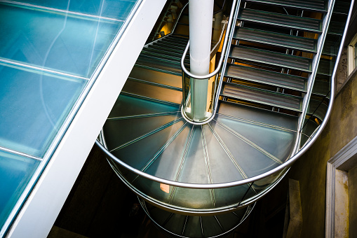 Color image depicting a modern metal spiral staircase in the city.