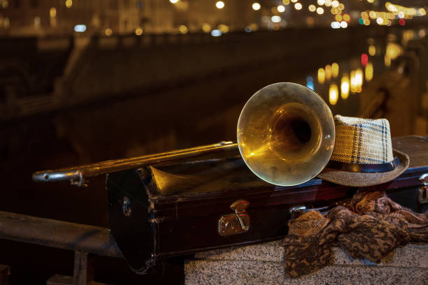 Trombone, case and men's hat on the background of the lights of the city's night channel