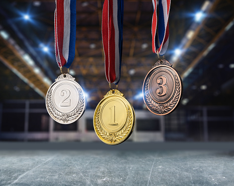 real Gold, silver and bronze medals hanging on red ribbons in an ice rink
