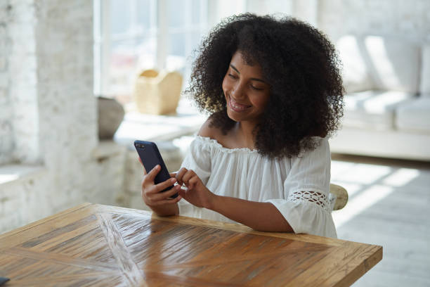 istock Relaxed afro american woman using mobile phone applications communicating in social network. 1354034881