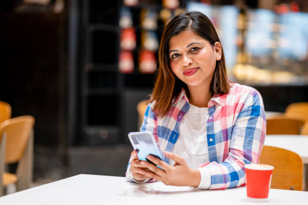 istock Young woman sitting at cafe and drinking coffee while using smartphone. 1354035364