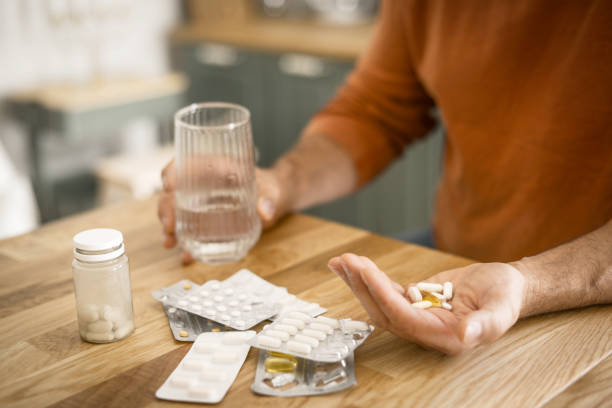 Mature adult man in cozy interior of home kitchen ( taking medication) stock photo