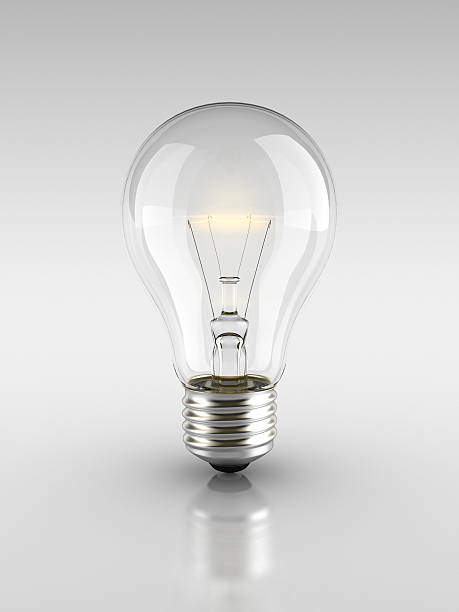 Lit light bulb on a grey background stock photo