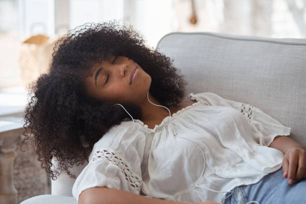 istock A relaxed young black smiling woman wearing headphones, resting on a comfortable couch 1354038310