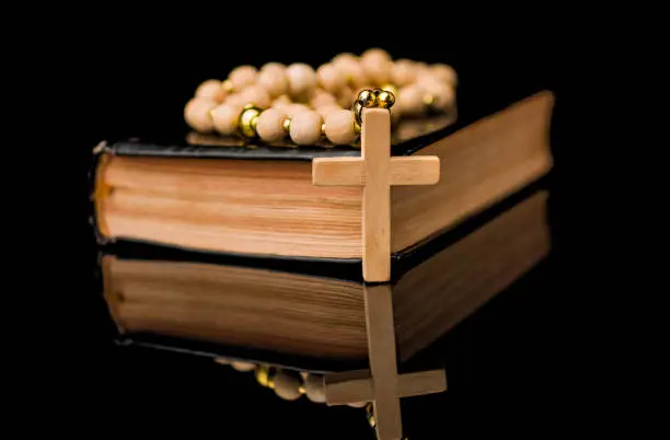 Closeup of wooden Christian cross on bible and prayer beads Church utensils.