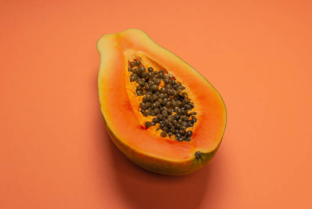 istock Papaya fruit on a orange background. Half papaya. 1354039083