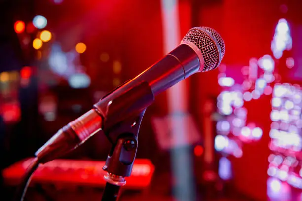 Photo of Microphone on the stage in the bar of the cafe restaurant with red colorful lighting