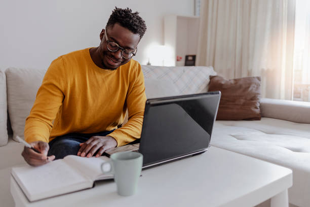 istock Smiling African American man working with laptop, browsing the internet at home office. 1354039889