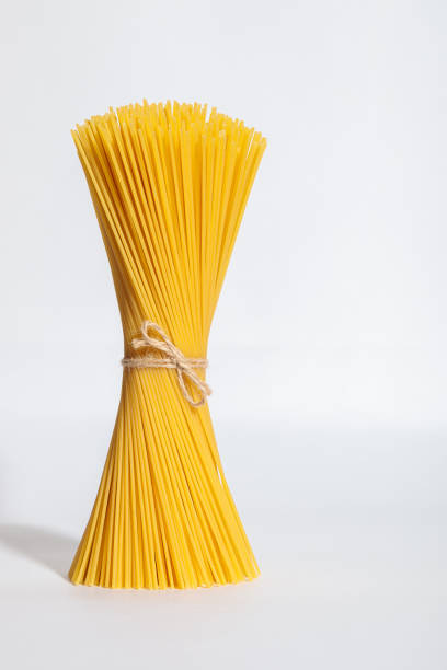 istock An upright bunch, a bunch of raw spaghetti tied with rope. Bundle on a white background. 1354041904