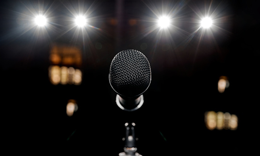 Beautiful microphone on stage and four beautiful spotlights shine in the background. High quality photo