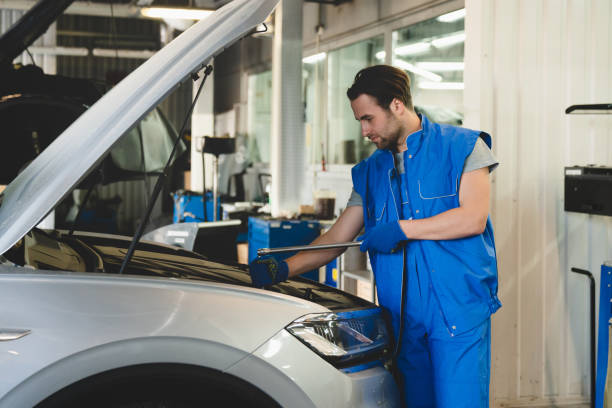 istock Successful confident young male car technician mechanic in special blue robe uniform holding pipe monkey wrench repairing fixing car at vehicle service inspection. 1354044538