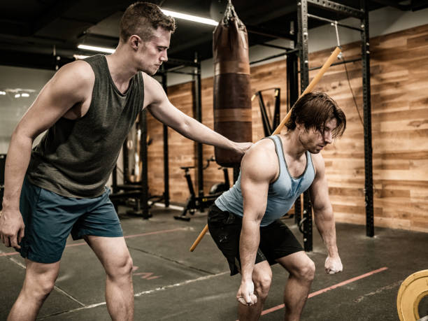 istock Young Man lifting weights with his trainer in the Gym 1354048257