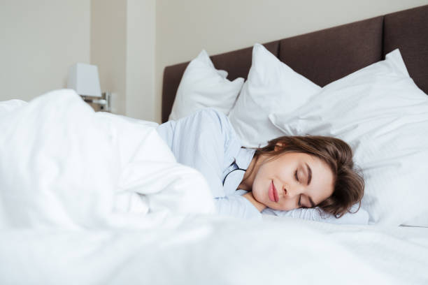 istock Cheerful young lady dressed in pajama sleeping in bed 1354052152