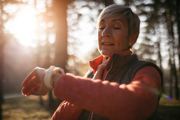 istock Fit Senior woman taking a break from jogging looking at smart watch 1354053218
