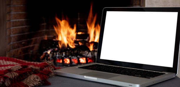 istock Christmas winter home office concept. Blank screen laptop on burning fireplace background, 1354053374