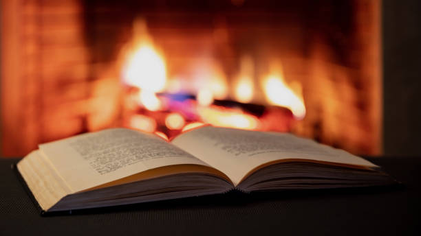istock Book open, fireplace burning firewood background. Reading and relax near the fire 1354053403