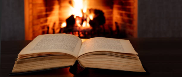 istock Book open, fireplace burning firewood background. Reading and relax near the fire 1354053408