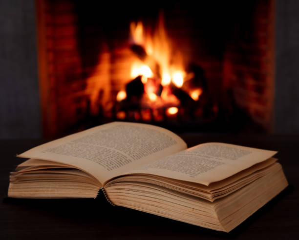 istock Book open, fireplace burning firewood background. Reading and relax near the fire 1354053427