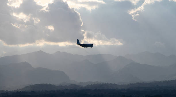 Silhouette of Aircraft in the Air Military propeller aircraft on final approach to Clark International Airport, with the Zambales Mountains in the distance - Clark, Pampanga, Luzon, Philippines zambales province stock pictures, royalty-free photos & images
