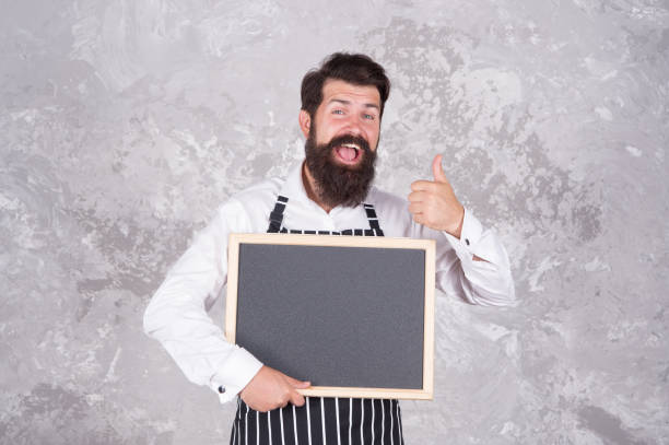 istock Man good looking hospitable restaurant waiter with blackboard copy space, recommend concept 1354056583