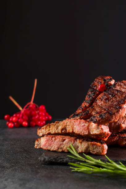 istock Meat cut on a stone board with rosemary and berries. Vertical position. Copy space. 1354057990