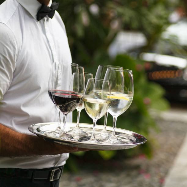 Luxury Living Waiter serving wine at a luxurious gathering. silver platter stock pictures, royalty-free photos & images