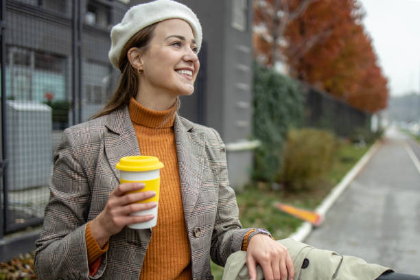 Modern Caucasian woman on electric scooter, holding coffee cup stock photo