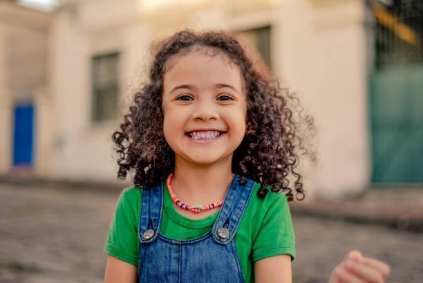 niña pequeña sonriendo en la calle. - little girls only fotos fotografías e imágenes de stock