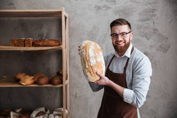 istock Cheerful young man baker standing at bakery holding bread 1354060566