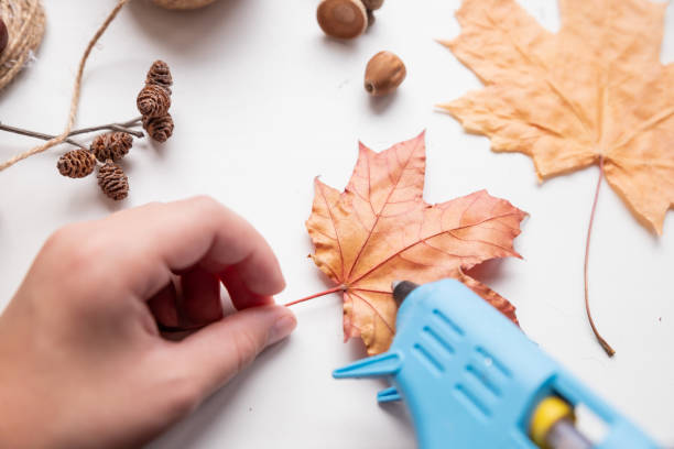istock Step by step DIY instruction for DIY craft. Autumn composition in glass.A gift from children.set of creativity.Step 3. a child glues maple leaves 1354063724