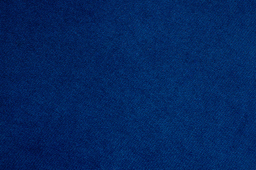 The texture of the fabric is velor in dark blue. Background Velvet upholstery furniture.