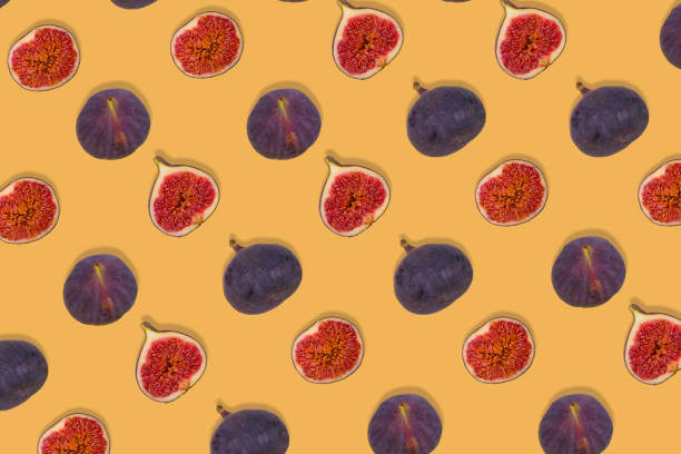 istock Creative pattern of fresh ripe whole and sliced figs on yellow background. 1354067289