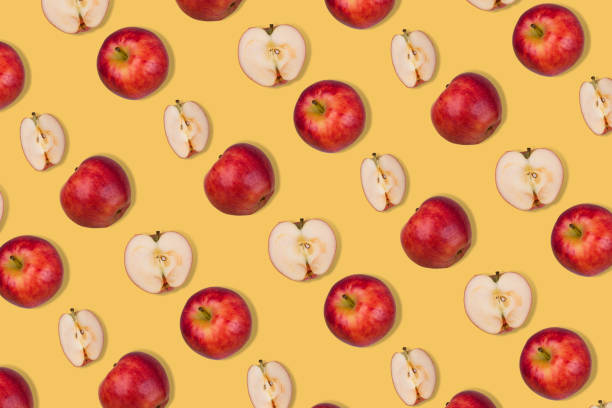 istock Pattern of fresh whole apple and halves on pastel yellow background. 1354067291
